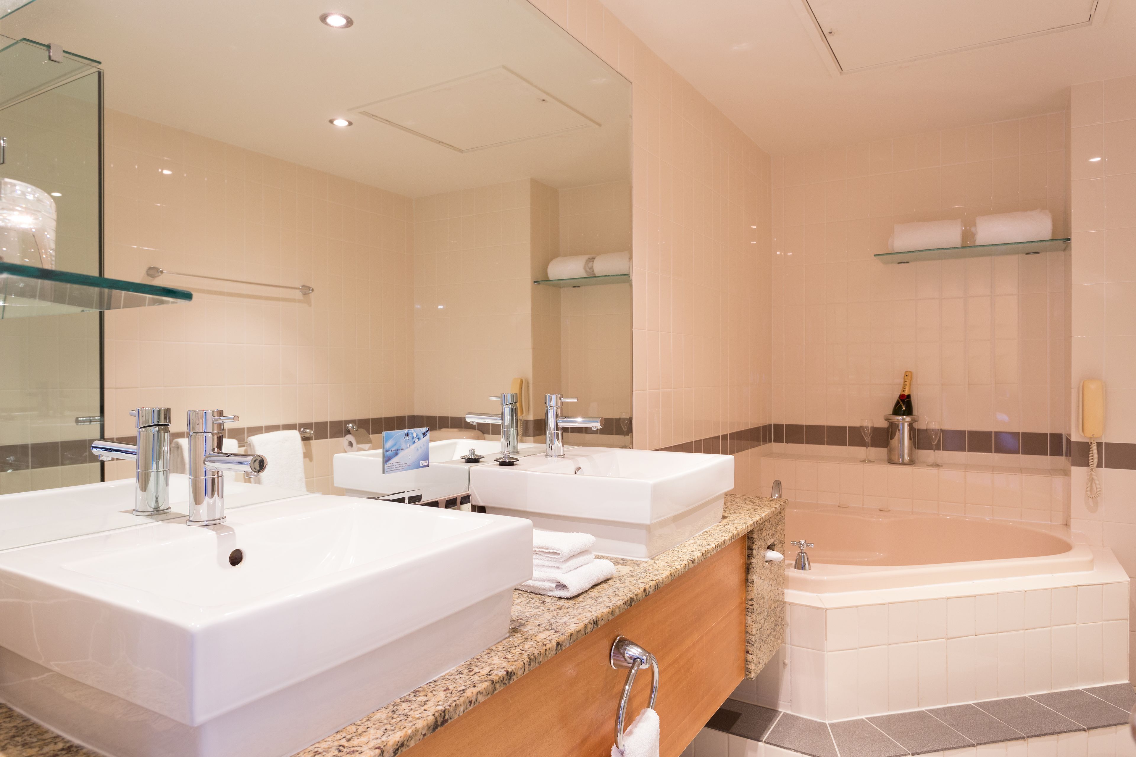 A modern bathroom with two sinks, a large bathtub, and a glass shower enclosure.