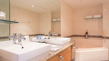 A modern bathroom with two sinks, a large bathtub, and a glass shower enclosure.