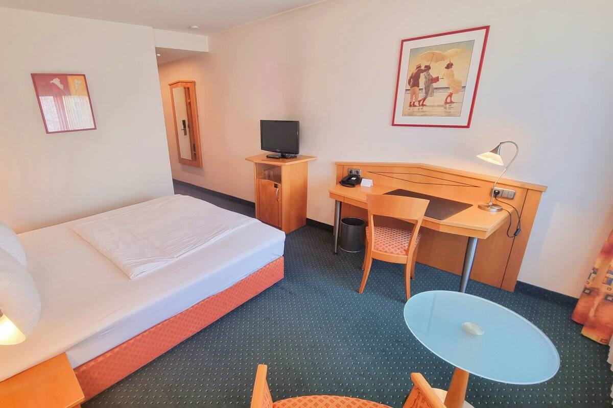 Ein Hotelzimmer mit Bett, Schreibtisch, Stuhl und einem kleinen Tisch.