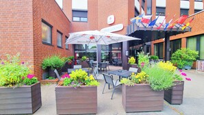 Un espace extérieur aménagé avec des tables et des chaises, entouré de jardinières fleuries.