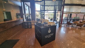 Un espace d’accueil d’hôtel avec un comptoir noir, une machine à café et un tableau noir servant de menu.