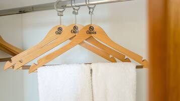 Wooden hangers with the word "Oasis" hanging on a metal rod.