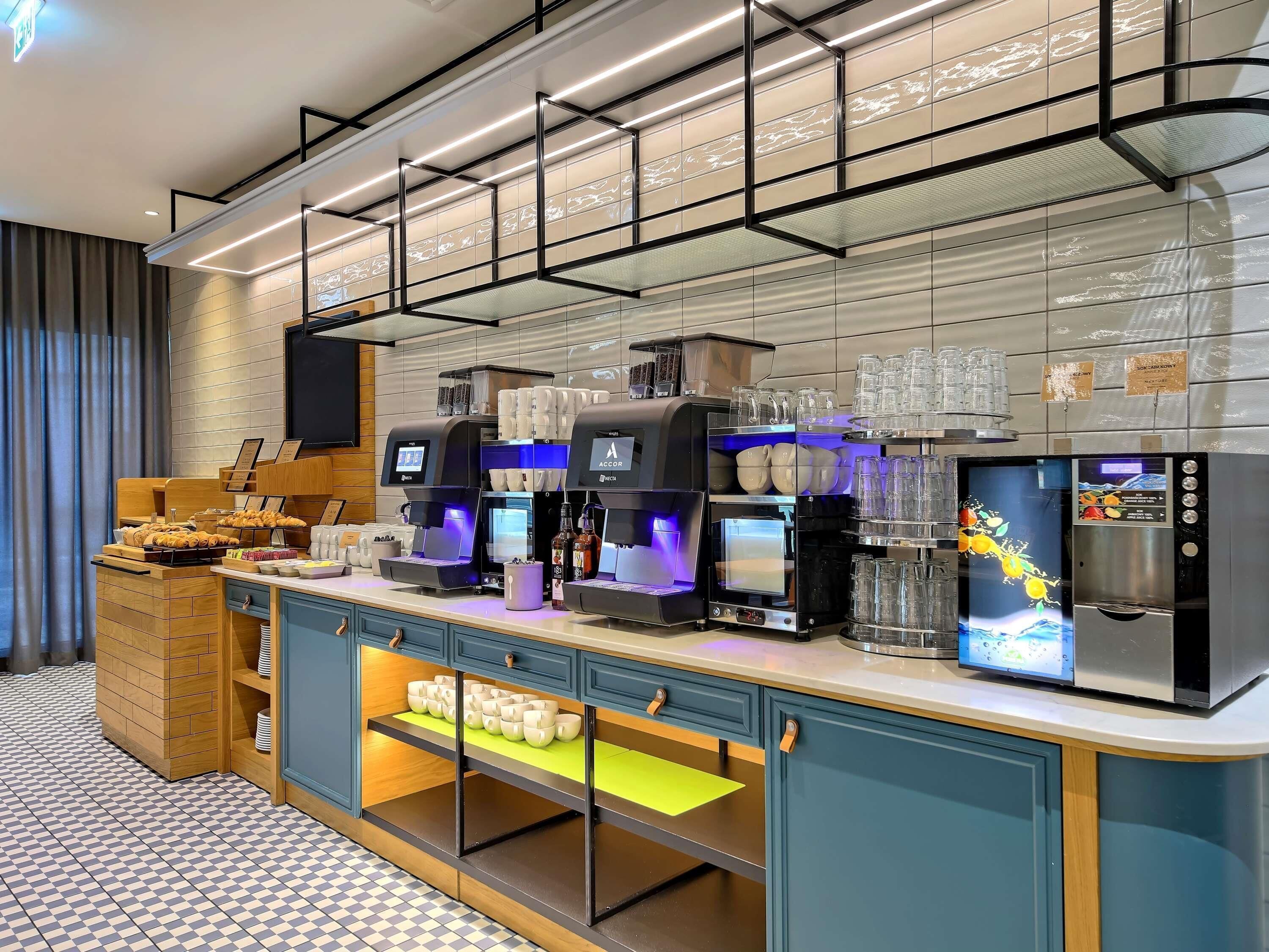 A modern coffee station with multiple espresso machines, a glass display case, and a counter with pastries.