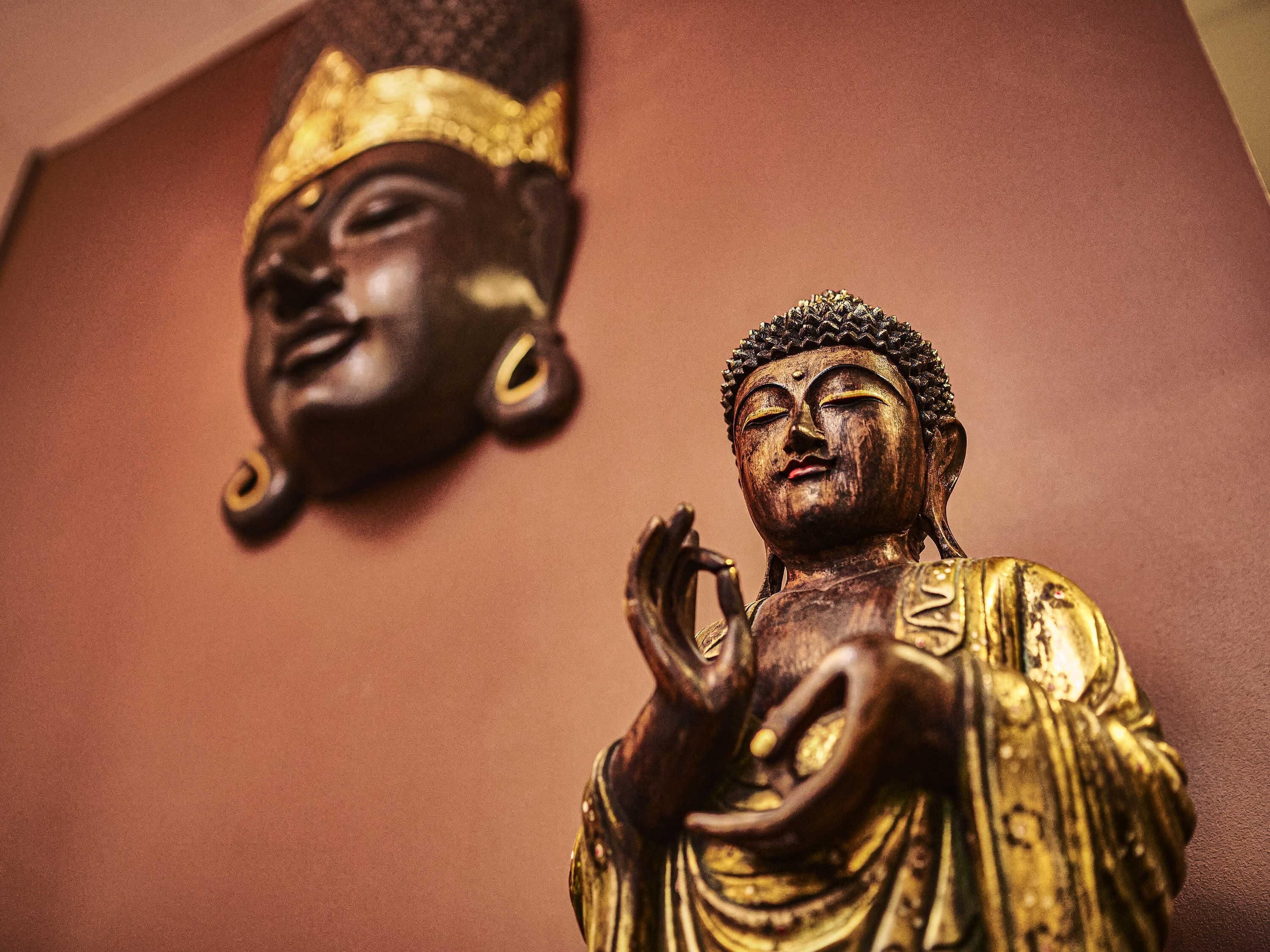 Two Buddha statues, one with a golden head and the other with a golden robe, both placed on a brown surface.