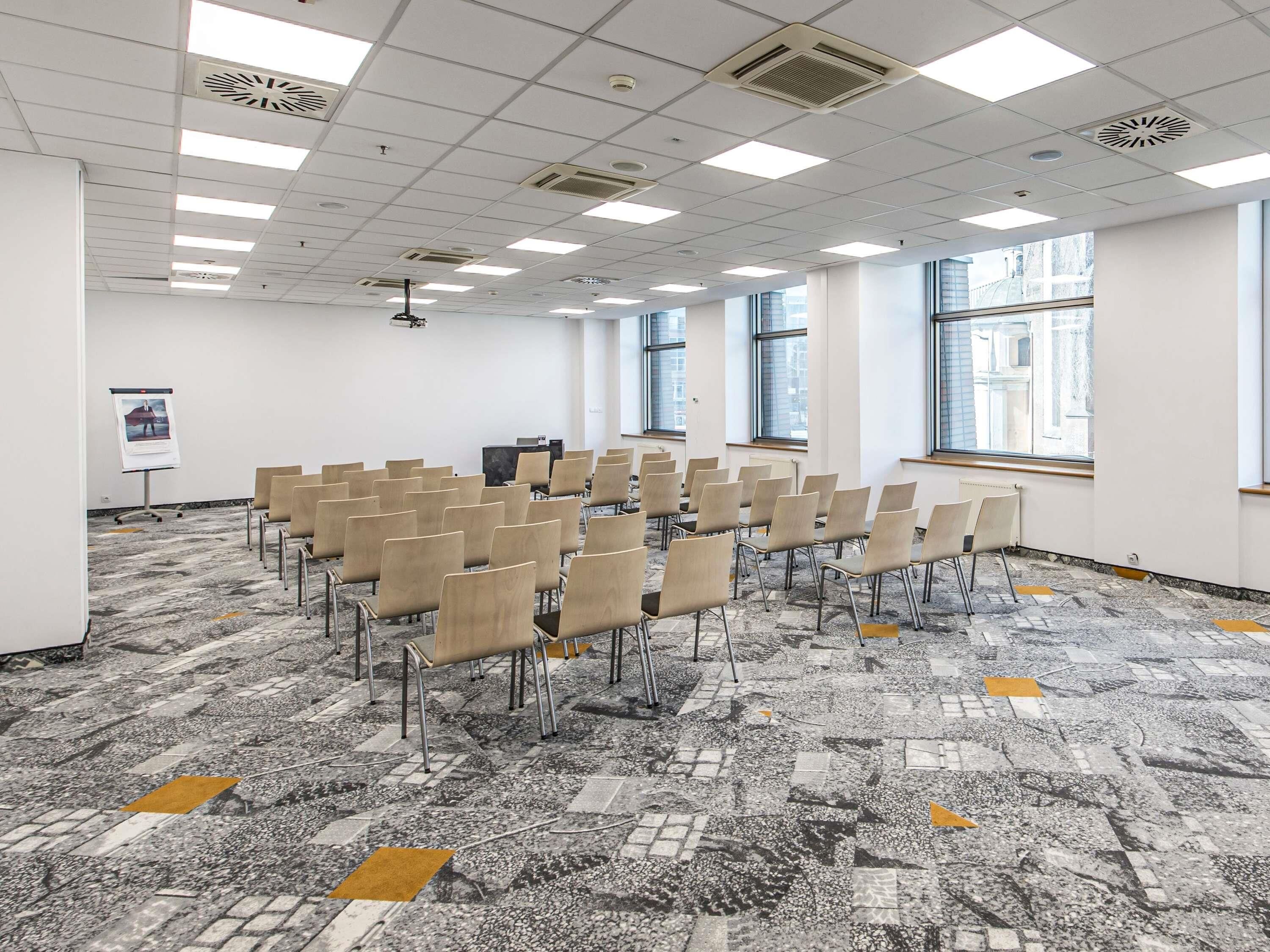 Una sala conferenze con file di sedie, un proiettore e uno schermo per presentazioni.
