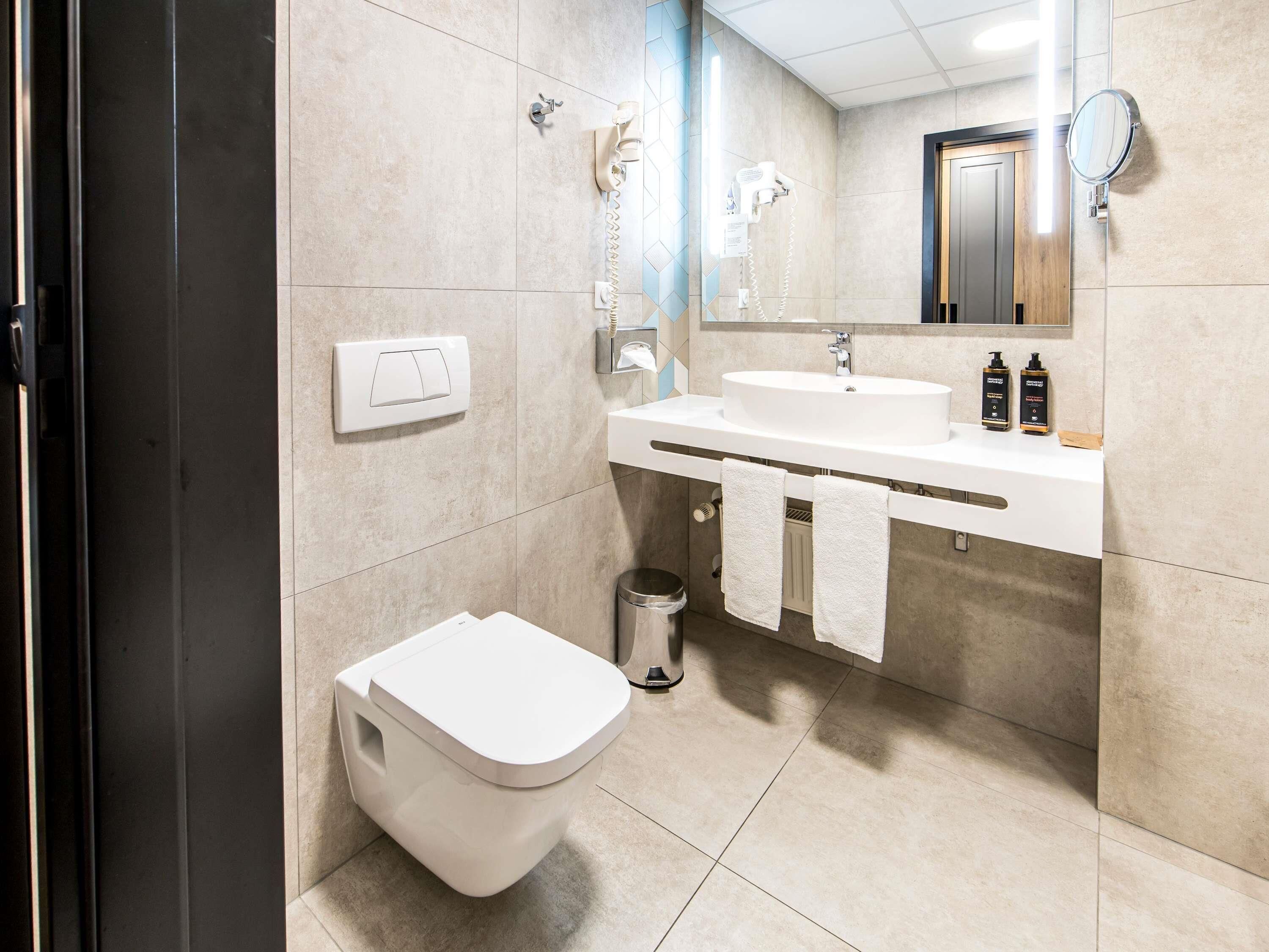 Une salle de bain moderne avec des toilettes, un lavabo et un miroir.