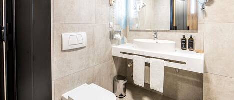 Un baño moderno con inodoro, lavamanos y espejo.