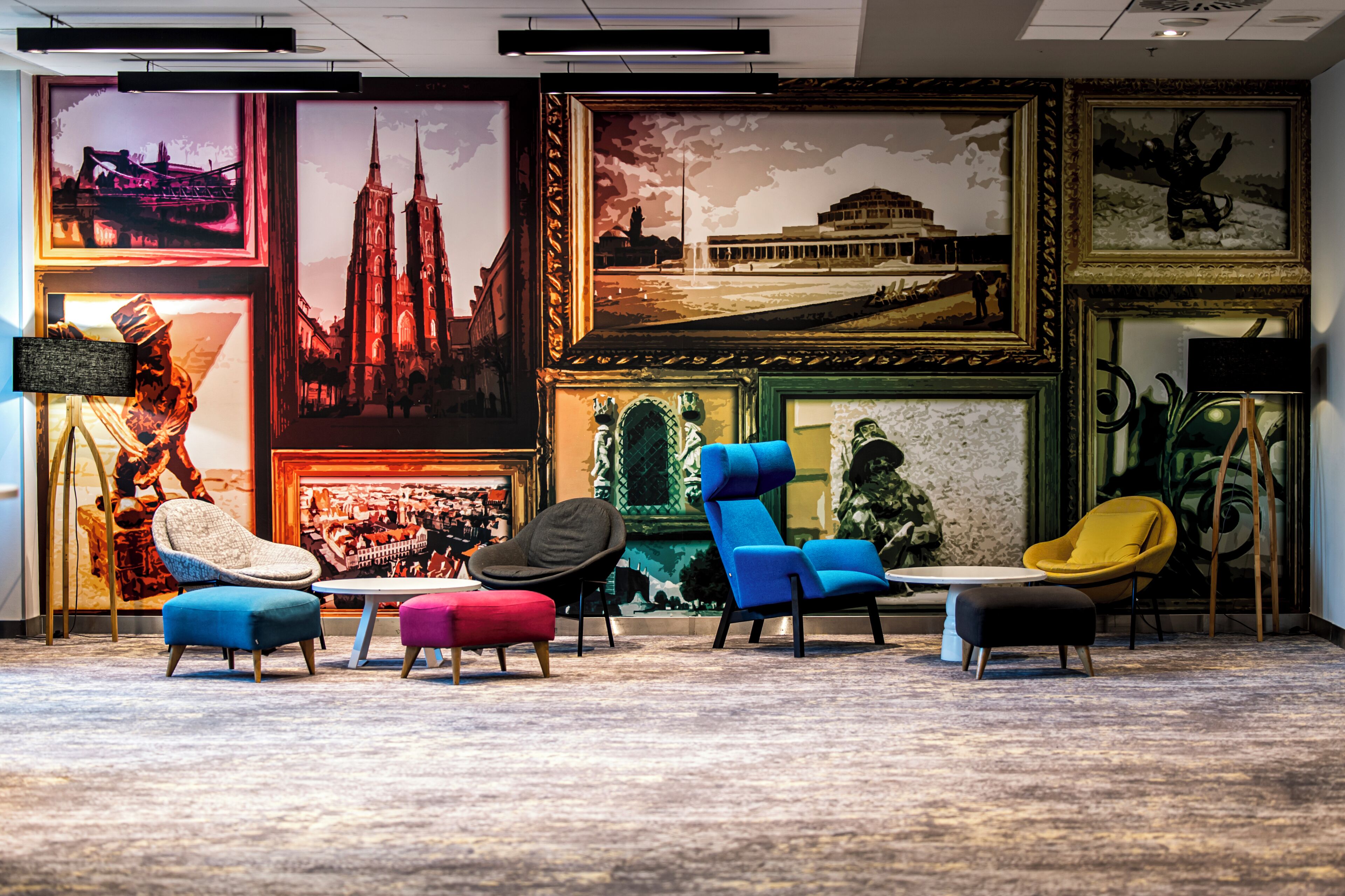 Un área de lounge moderna con sillas y otomanas coloridas, obras de arte enmarcadas en las paredes y una estatua.