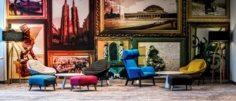 Un área de lounge moderna con sillas y otomanas coloridas, obras de arte enmarcadas en las paredes y una estatua.
