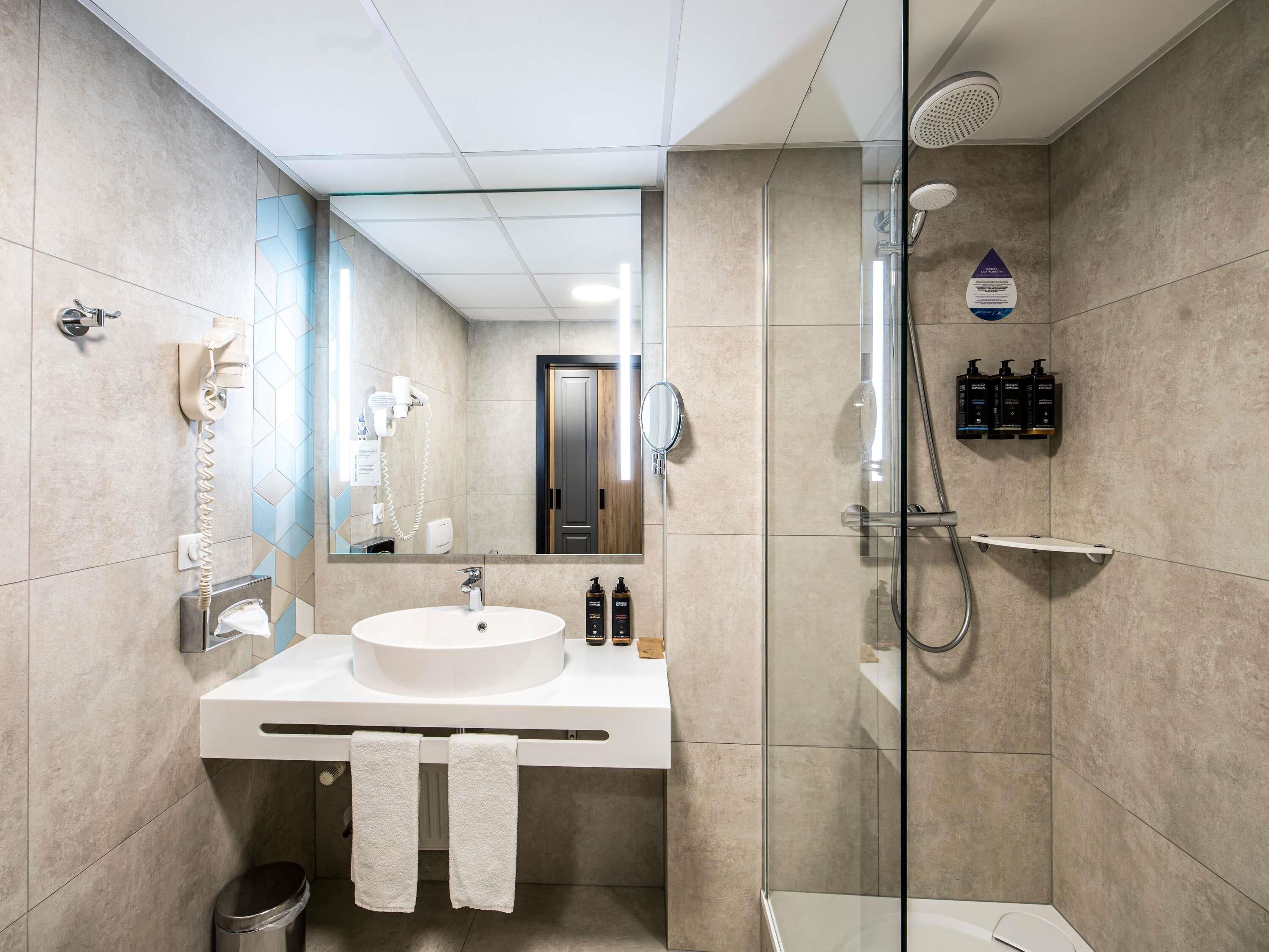 Ein modernes Badezimmer mit großem Spiegel, Waschbecken, Dusche und Toilette.