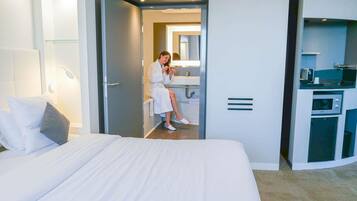 Une chambre d’hôtel avec un grand lit, une salle de bain avec un miroir et une kitchenette équipée d’un four à micro-ondes.