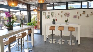 Un moderno espacio de bar con una mesa blanca, taburetes y lámparas colgantes.