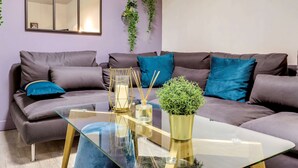 Una sala moderna con una mesa de centro de vidrio, sofás grises y cojines azules.