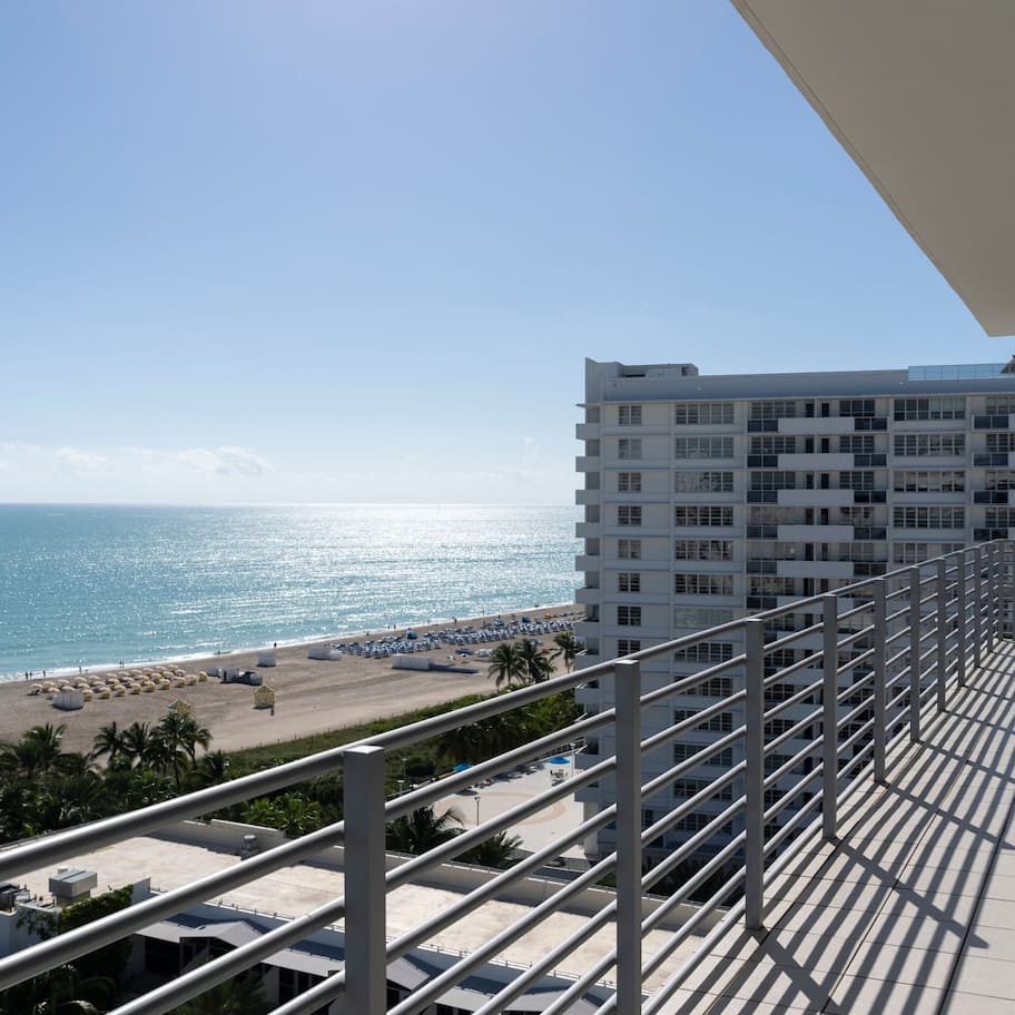 A balcony with a view of the beach and ocean.
