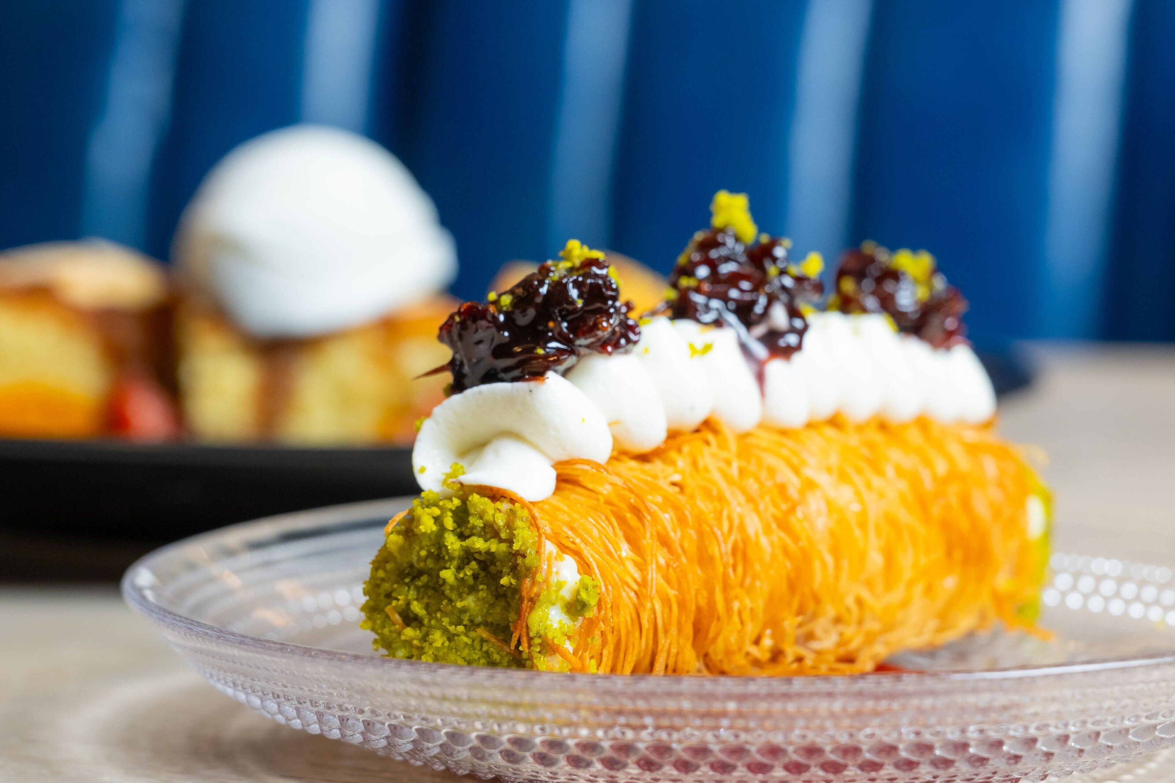 Ein Dessert mit cremiger Glasur und grüner Basis, serviert auf einer transparenten Glasschale.