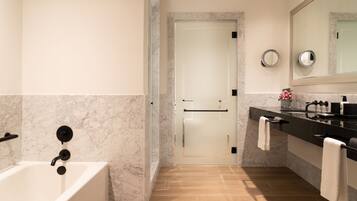 Une salle de bain moderne avec une baignoire, un meuble-lavabo avec un miroir et une porte donnant sur une autre pièce.