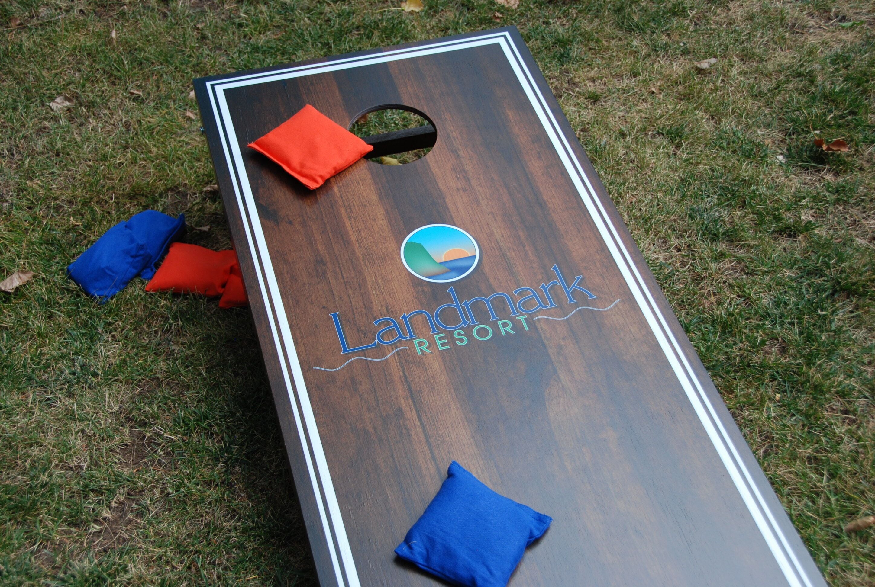 A wooden board game with the text "Landmark Resort" and a logo, placed on grass.