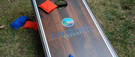 A wooden board game with the text "Landmark Resort" and a logo, placed on grass.