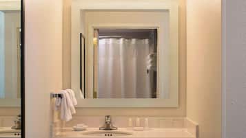 Un baño con espejo, lavamanos y cortina de ducha.
