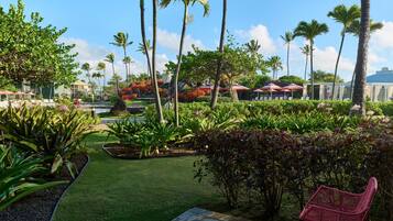 A tropical garden with palm trees, a pool, and outdoor seating.