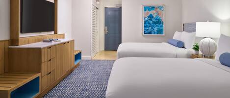 Una habitación de hotel con televisión, dos camas, un cuadro, una lámpara y una planta pequeña.