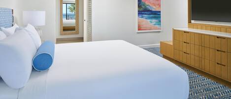 A hotel room with a large bed, a TV, a wooden cabinet, and a painting of a beach scene.