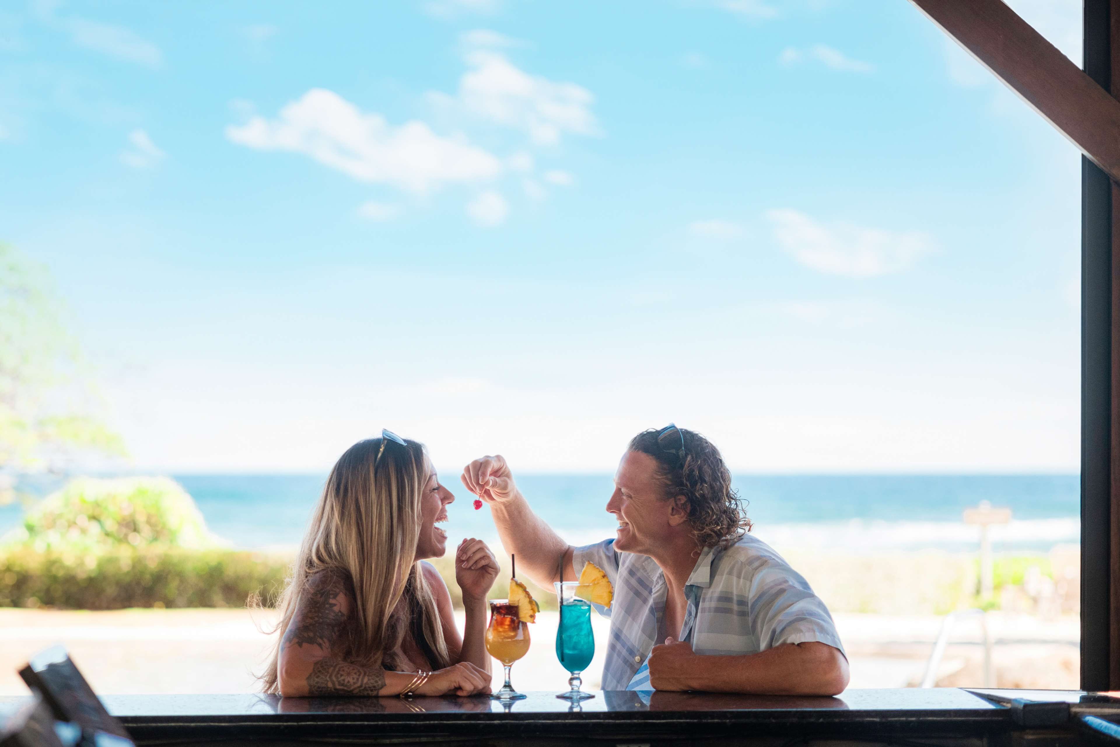 Two people at a bar with a view of the ocean.