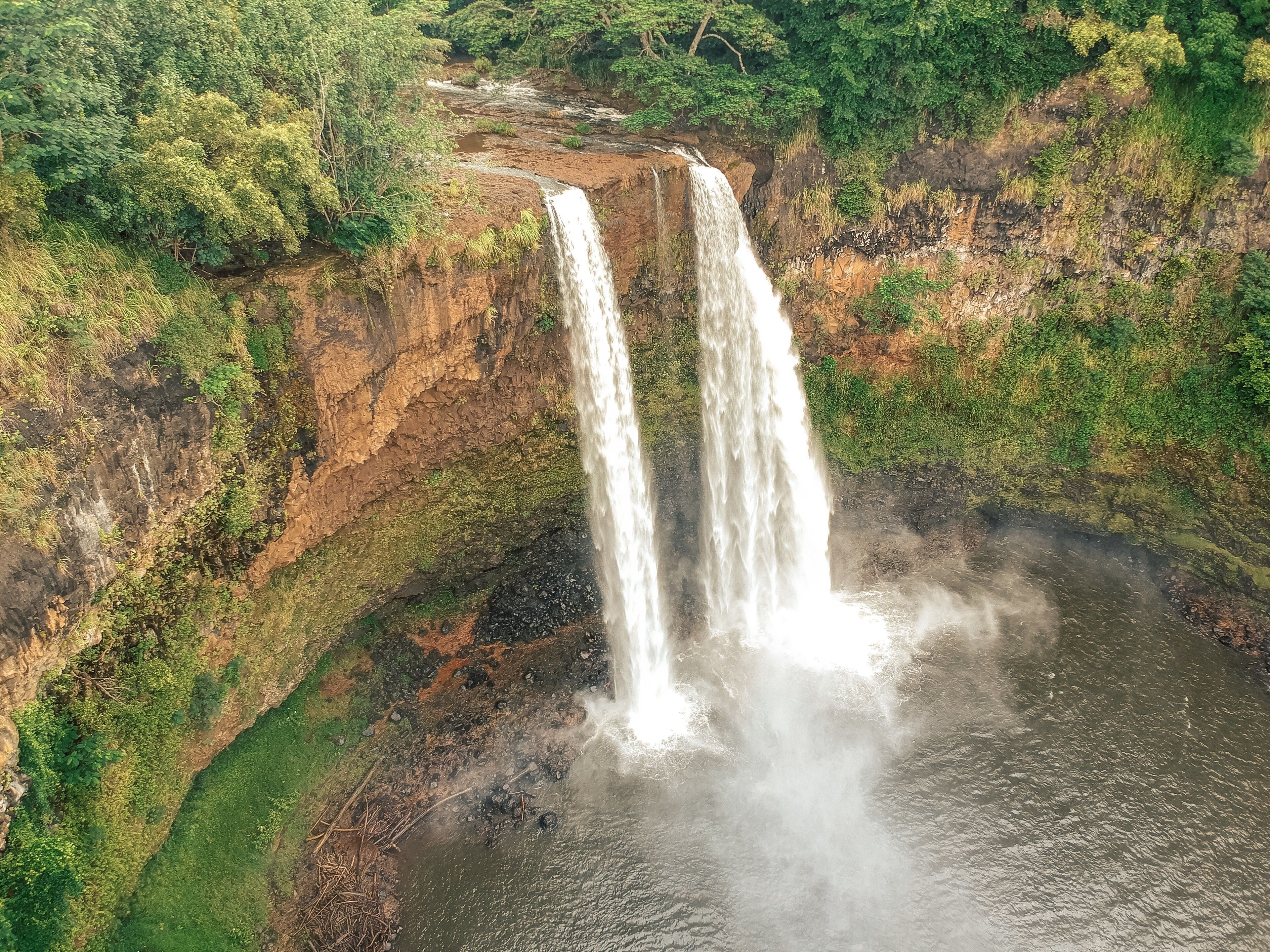 A waterfall cascading down a rocky cliff surrounded by dense greenery.