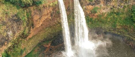 A waterfall cascading down a rocky cliff surrounded by dense greenery.