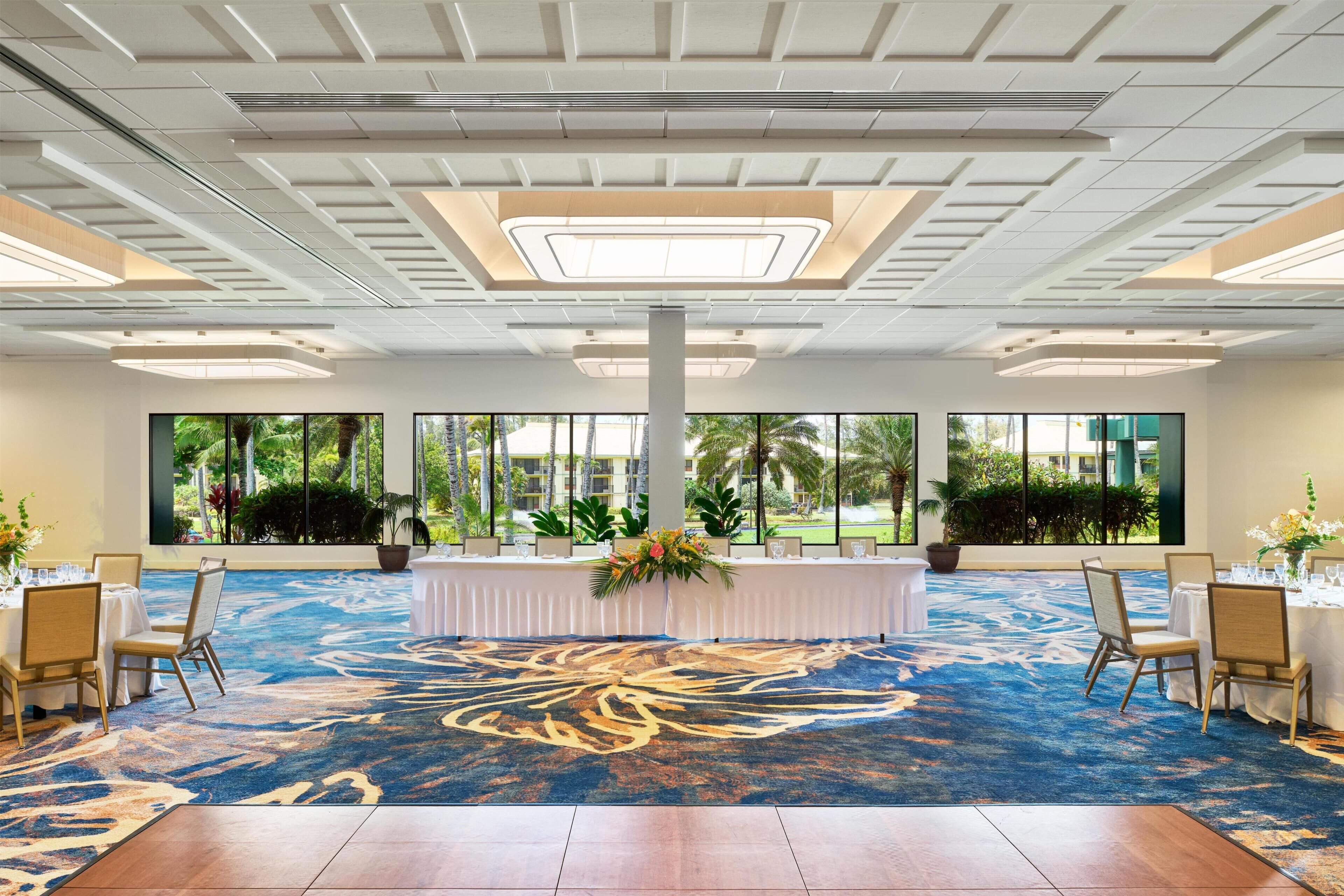 A conference room with a large table, chairs, and a carpet with a floral pattern.