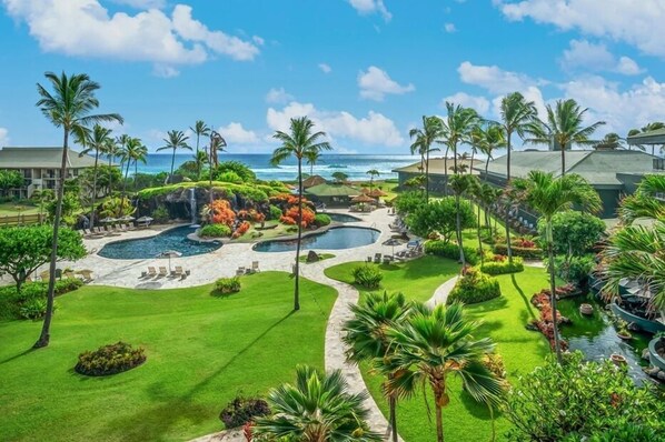 Un resort con piscina, palmeras y vista al océano.