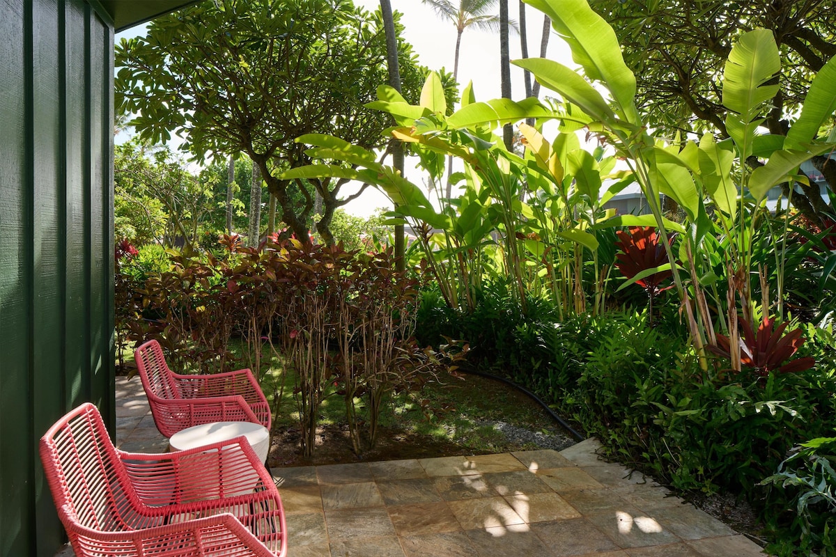A patio with red wicker chairs and a small water feature.
