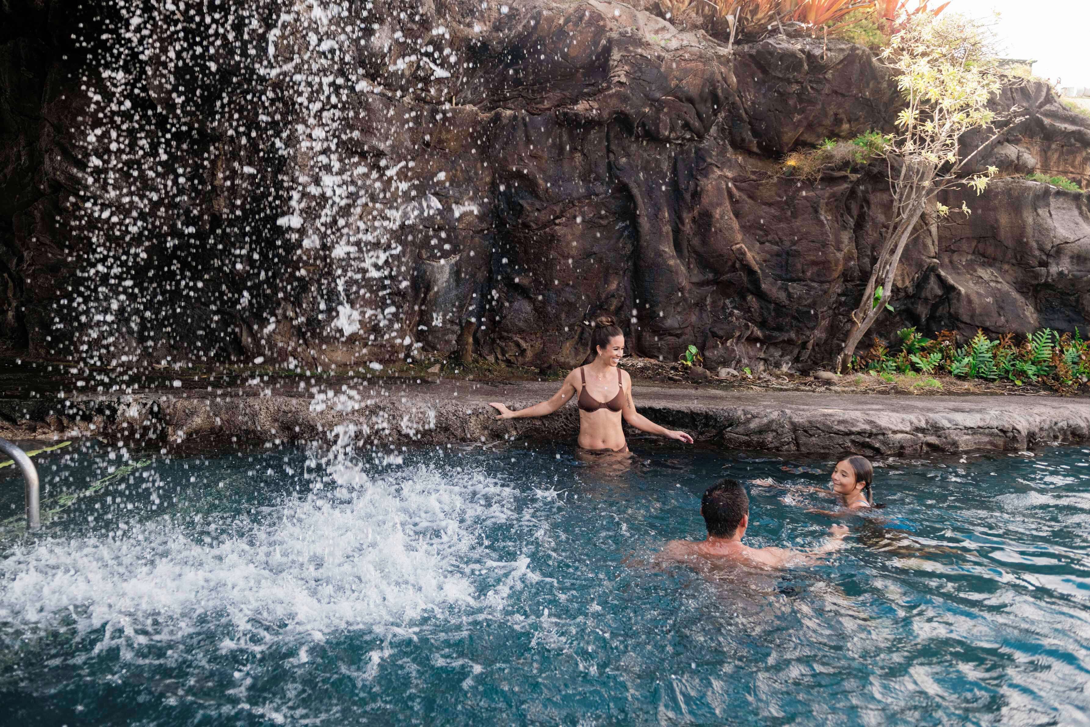 Una piscina con una cascata, immersa in un paesaggio roccioso.