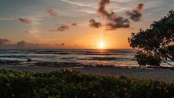A sunset over the ocean with a beach in the foreground.