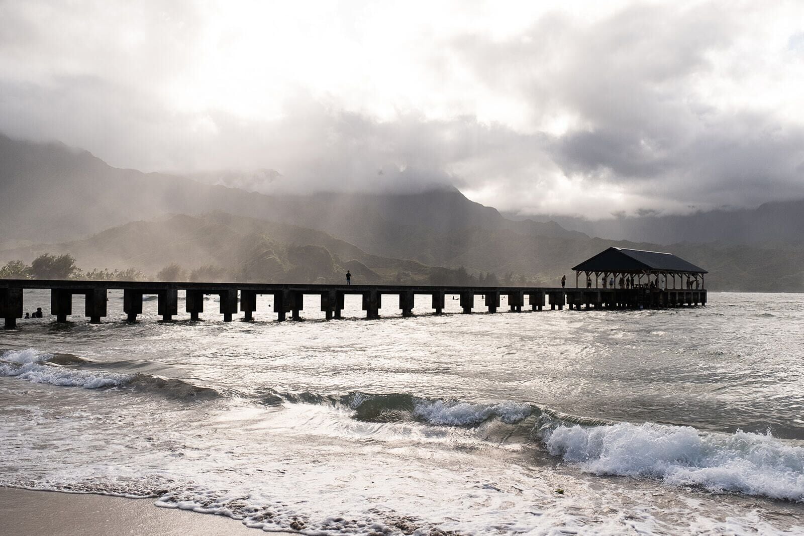 Un muelle que se adentra en el agua, con olas rompiendo en la orilla.