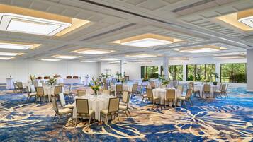 A large conference room with round tables, chairs, and a blue carpet.