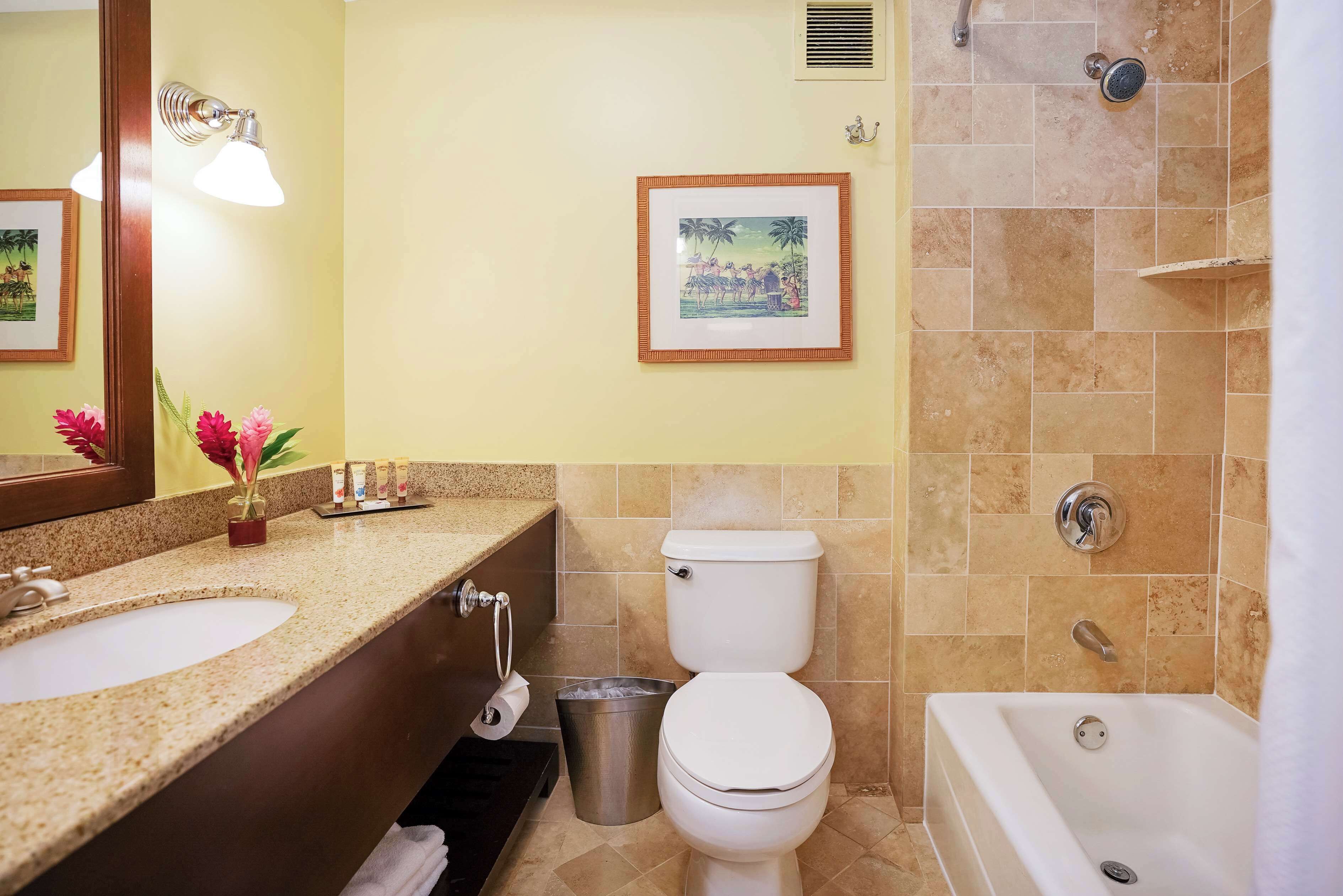 A bathroom with a sink, toilet, bathtub, and a framed picture on the wall.