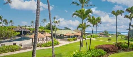 A resort with a pool, palm trees, and a view of the ocean.