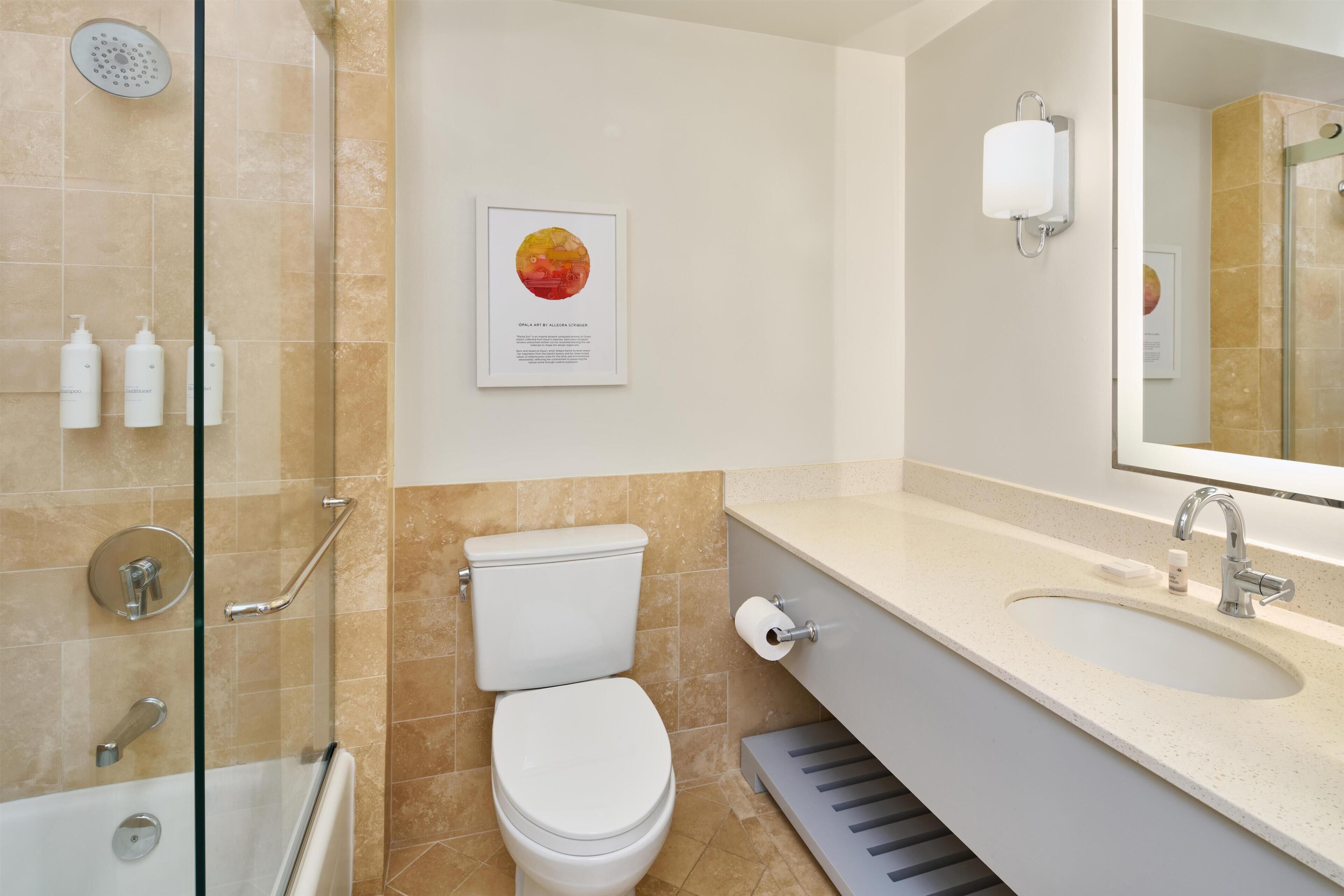 Un baño con ducha, inodoro, lavamanos y un espejo grande.