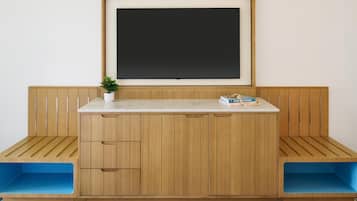 A room with a wooden bench seating area, a white desk with drawers, and a framed blackboard on the wall.