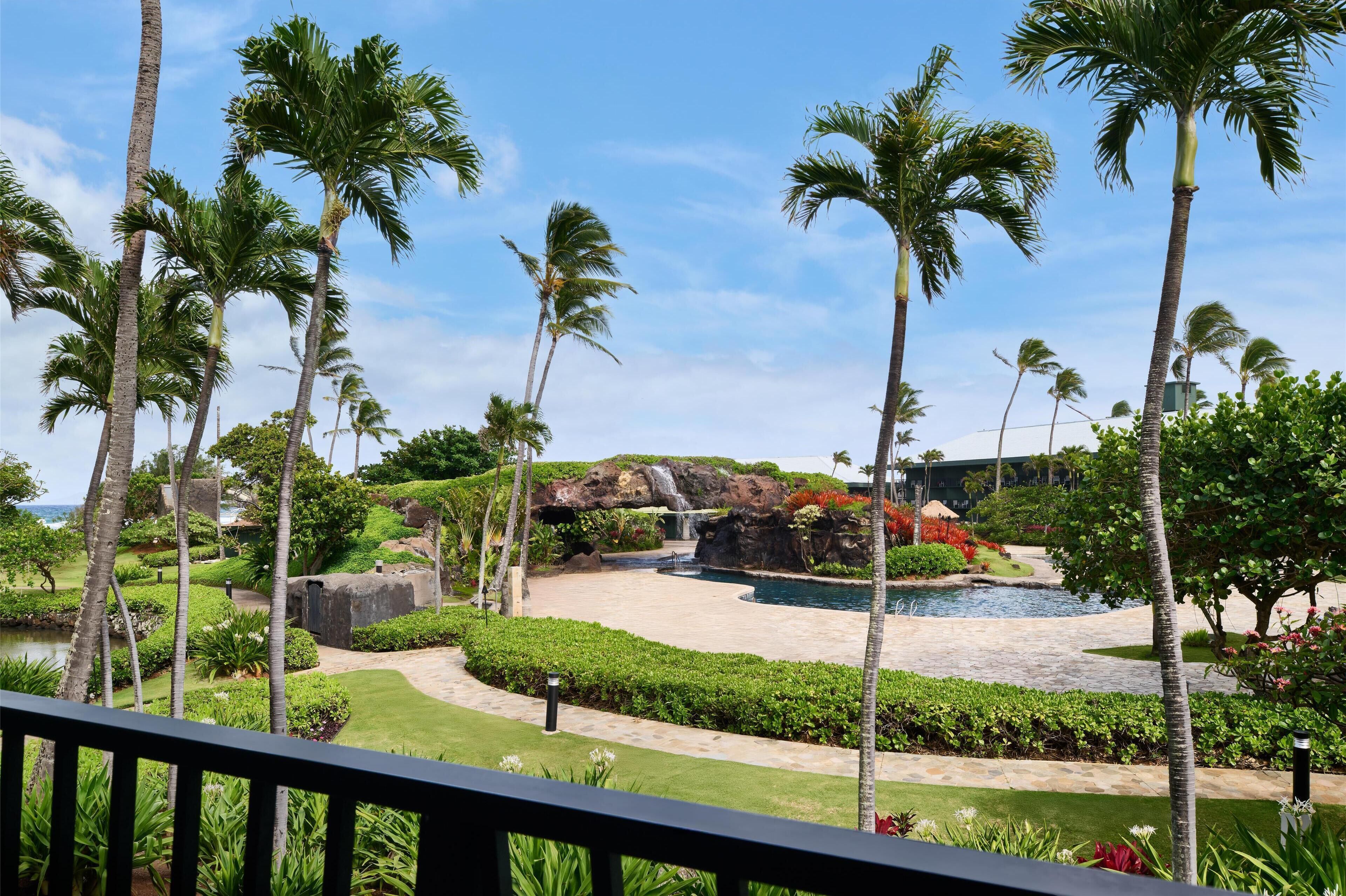A tropical resort with palm trees, a waterfall, and a pool.