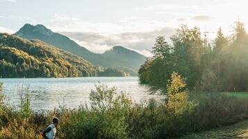 Un corredor en un sendero de grava junto a un lago, con montañas al fondo.