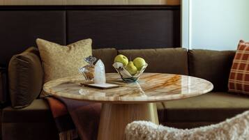 A round marble table with a bowl of green pears, a crystal, and a white napkin.