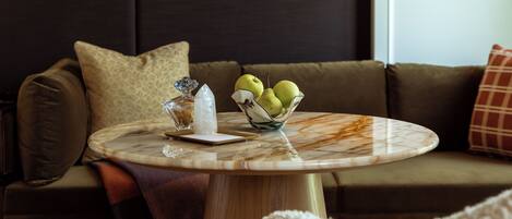 A round marble table with a bowl of green pears, a crystal, and a white napkin.