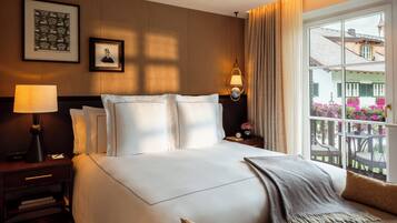 Ein Hotelzimmer mit einem großen Bett, einem Nachttisch mit Lampe, einem gerahmten Bild und Blick auf den Balkon.