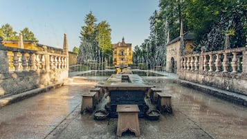 Un patio con una fuente, bancos de piedra y un edificio al fondo.