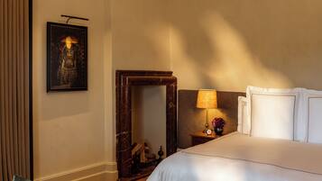 A neatly arranged hotel room with a large bed, a bedside table with a lamp, a framed picture on the wall, and a mirror.