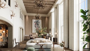 Uma sala de estar espaçosa com um sofá grande, um candelabro e uma janela ampla com cortinas.