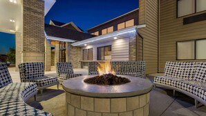 A circular outdoor seating area with a fire pit, surrounded by patterned sofas and chairs.