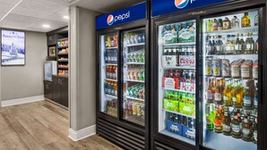 A hotel lobby with Pepsi refrigerators stocked with beverages and snacks, a television, and a display of American Inn brand decor.